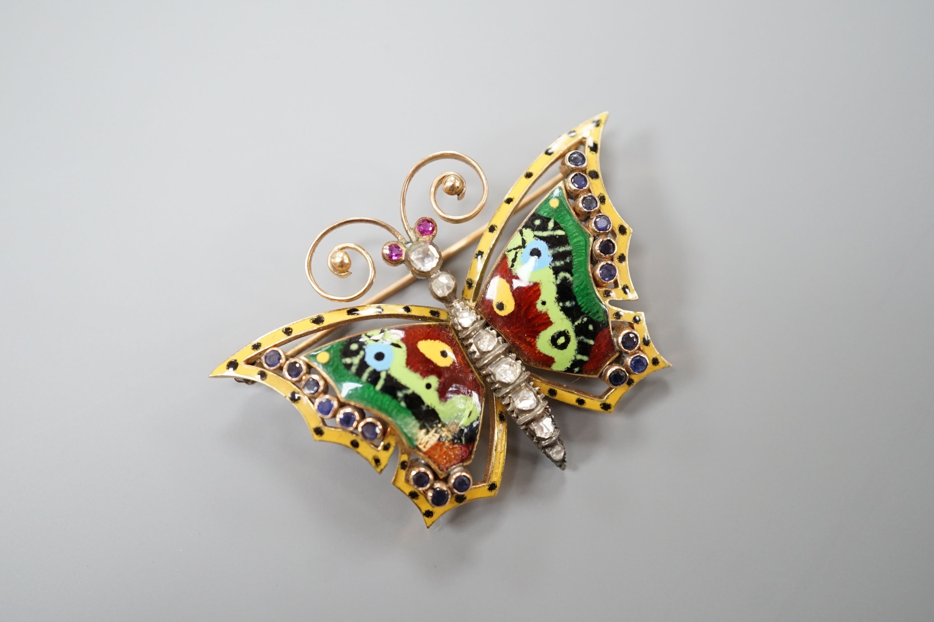 A continental yellow metal, polychrome enamel, rose cut diamond and gem set butterfly brooch (a.f.), width 50mm, gross weight 13.8 grams.